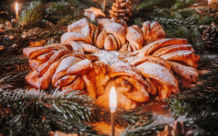 Een brood in de vorm van een kerstster. Daar omheen dennengroen en kaarsjes.
