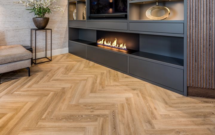 Hoek van een sfeervolle woonkamer met een donkere wandkast, gevuld met kunst, verlichting en een sfeerhaard