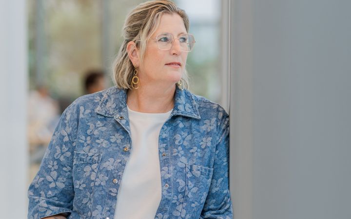 Vrouw in blauw jasje met bloemenprint.