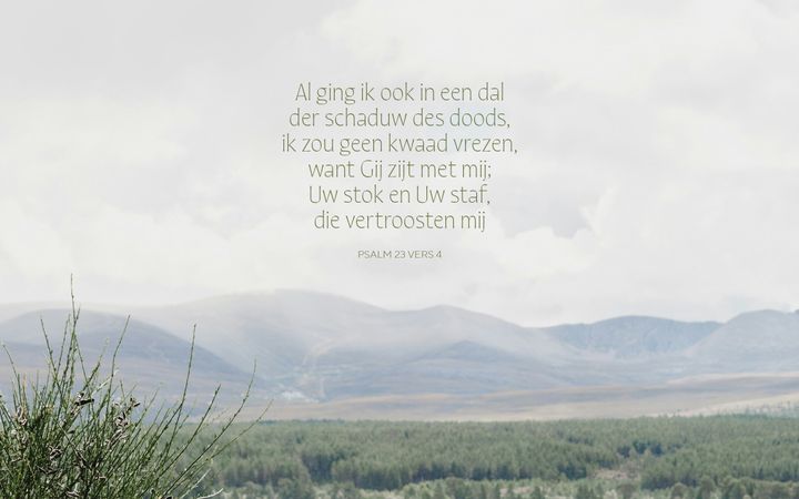 Een berglandschap met op de voorgrond gras. In de lucht staat de tekst uit Psalm 23:4: ‘Al ging ik ook in het dal der schaduw des doods, ik zou geen kwaad vrezen, want Gij zijt met mij, Uw stok en Uw staf, die vertroosten mij. 