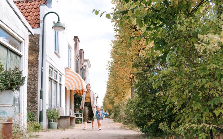 Jonge vrouw, wandelend in een oud straatje, met een meisje naast zich.