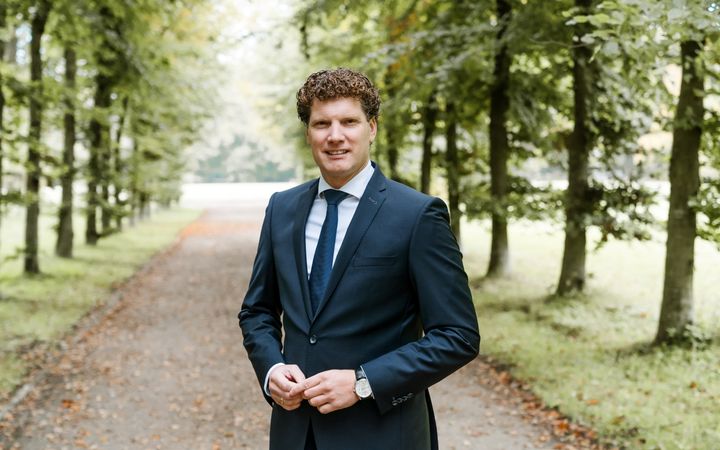 MAN IN BLAUW PAK IN EEN OPRIJLAAN 