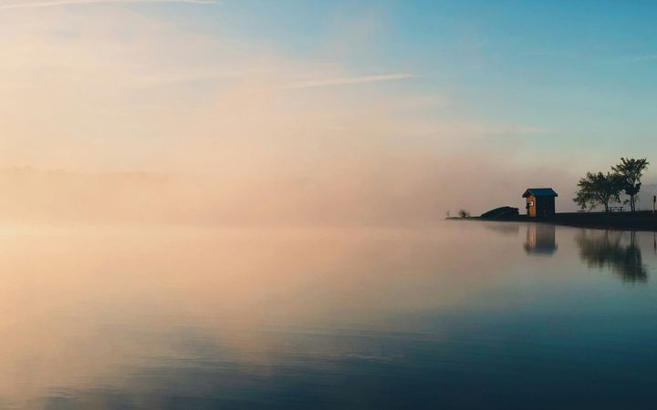 Huisje aan het water met mist