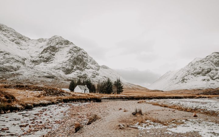 Heuvellandschap met sneeuw en een wit huis.