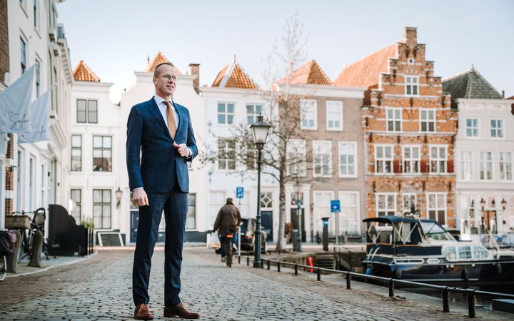Man in blauw pak voor historische panden in de haven van Goes.