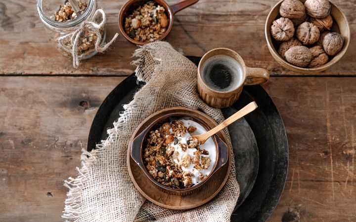 Schaal met granola en een kop koffie op een dienblad.