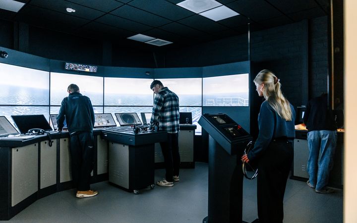 Drie jongens en een meisje in de simulator van de brug op een zeeschip.