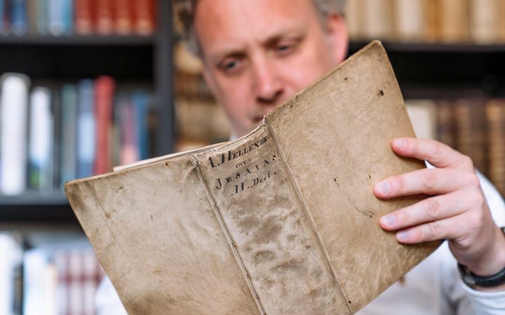 Man leest uit een oud boek met omslag van perkament.