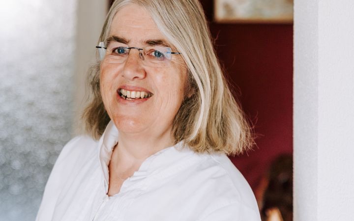 Portret van vrouw met blond haar en witte blouse.