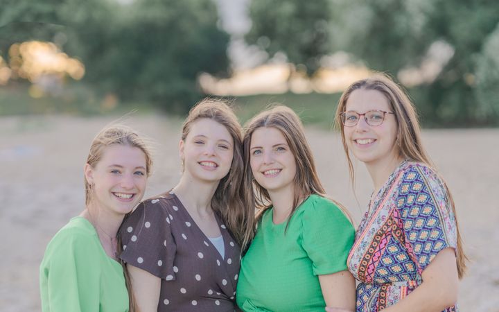 Vier jonge vrouwen op een rij; alle drie met lang, donkerblond haar. De rechtervrouw draagt een bril. 