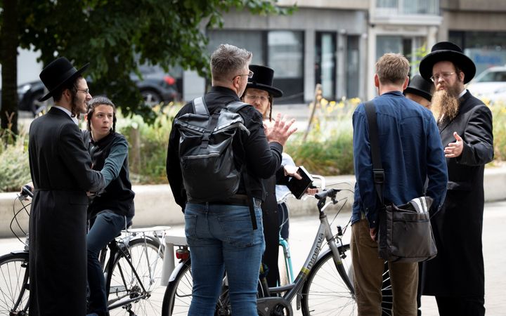 Twee jonge mannen in gesprek met orthodoxe Joden.