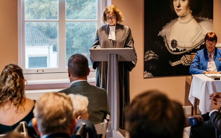 Judith Klokkenburg staat voor een katheder en leest de toespraak voor die ze schreef voor het huwelijk van Frank en Elisa van Vliet.